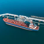 Aerial view of a tanker docked at oil port facilities for cargo transfer.
