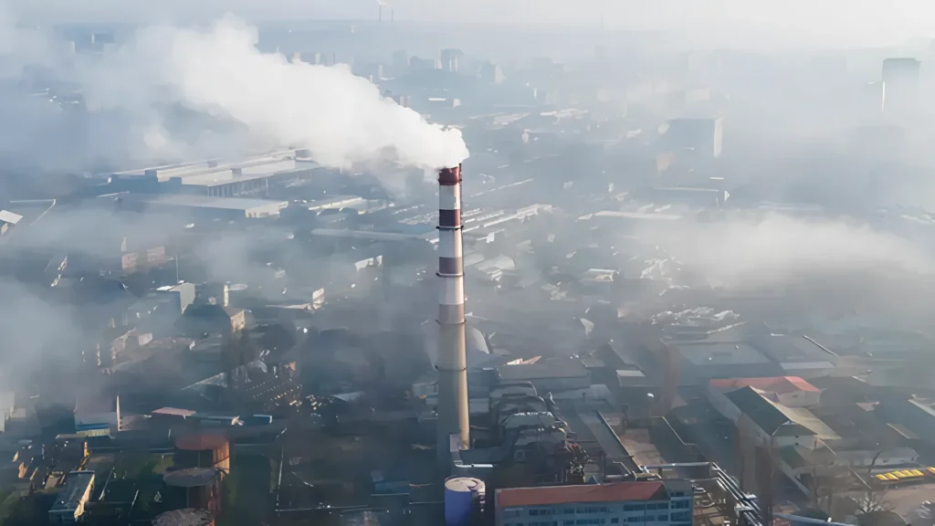 Chimenea industrial emitiendo humo en una zona urbana, ilustrando la necesidad de tecnologías avanzadas como quantum LiDAR para la detección precisa de emisiones de metano.
