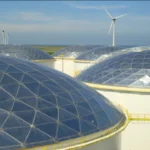 Coteso aluminum geodesic domes installed on storage tanks, with perimeter walkways and wind turbines in the background.