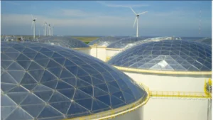 Coteso aluminum geodesic domes installed on storage tanks, with perimeter walkways and wind turbines in the background.