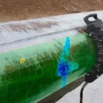 Técnico inspeccionando una tubería con tecnología Eddy Current Array, mostrando defectos internos codificados por colores en la superficie del acero inoxidable.