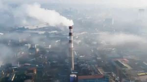 Industrial chimney emitting smoke in an urban area, illustrating the need for advanced technologies such as quantum LiDAR for accurate detection of methane emissions.