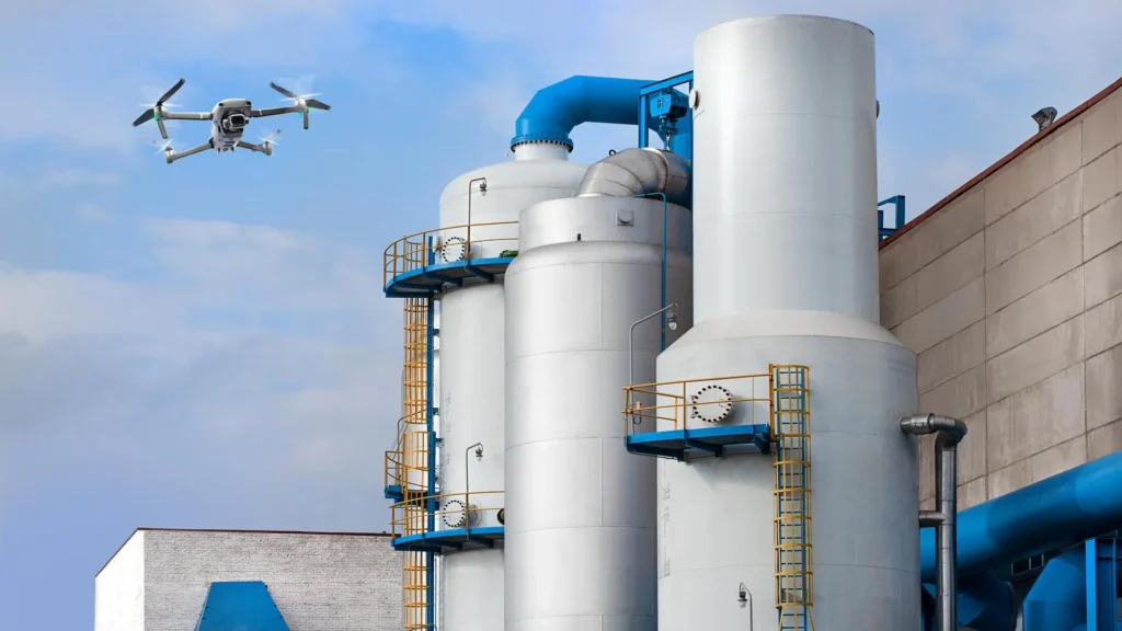 Drone performing non-destructive inspection of industrial storage tanks at an energy facility as part of an NDT 4.0 strategy.