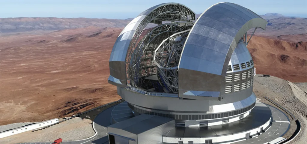 Vista exterior del telescopio más grande del mundo en construcción en el desierto de Atacama, Chile, con su cúpula parcialmente abierta mostrando la estructura del telescopio.