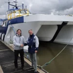 Matt Holland de Aqua superPower y Leo Hambro de Tidal Transit frente a un buque eléctrico E-CTV para operaciones offshore.