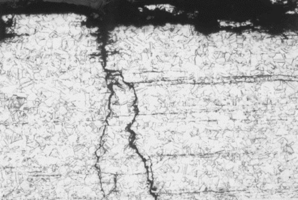 Micrograph of an intergranular crack in a metal, associated with damage mechanisms such as stress corrosion cracking, relevant in refinery equipment according to API 571.