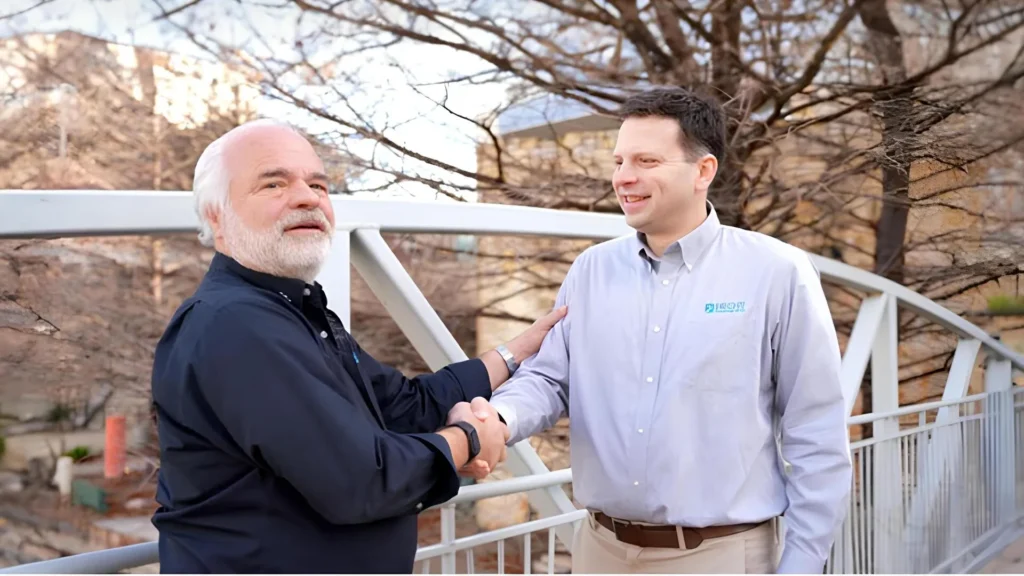 Charles Becht V shakes hands with an associate in a gesture of trust and leadership during Becht's 60th anniversary commemoration.
