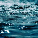 La superficie del agua reflejando la luz, simbolizando la ilusión de abundancia de agua y el papel oculto de las aguas subterráneas en una crisis creciente de escasez de agua.