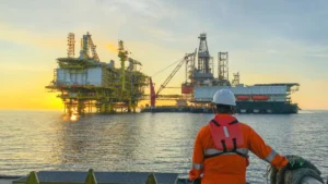 Trabajador observando plataformas offshore en operación durante el amanecer.