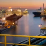 View of a CALM Buoy SPM offshore terminal at sunset, with illuminated industrial structures over the sea and pipelines in the foreground, representing the importance of the human factor in the safe management and operation of these facilities.
