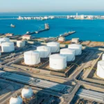 Vista aérea de tanques optimizados de almacenamiento industrial junto a un puerto.