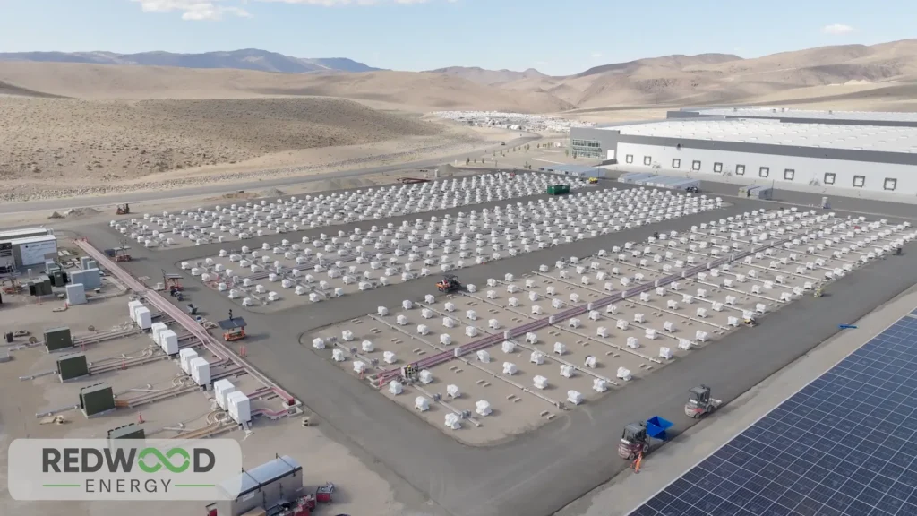 Vista aérea de una instalación industrial de Redwood Energy con cientos de módulos de almacenamiento de baterías EV y paneles solares en un entorno desértico.