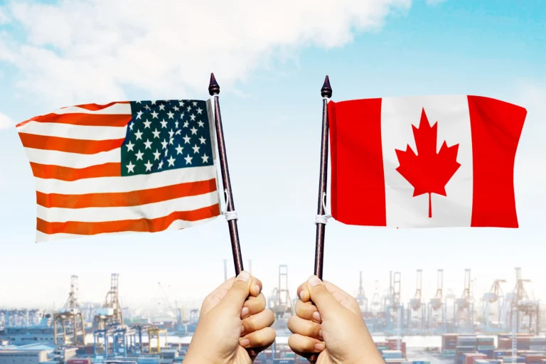 Banderas de U.S. y Canadá frente a infraestructura comercial y portuaria.