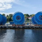 Carretes industriales con sistemas umbilicales de SLB OneSubsea preparados para proyectos submarinos en aguas profundas.