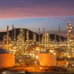 Refinería con tanques de almacenamiento de crudo mientras los Oil prices reaccionan a la incertidumbre sobre Irán y las previsiones de la AIE.
