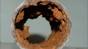 Microbiologically influenced corrosion (MIC). Cross-section of a heavily corroded pipe with extensive rust and material degradation.